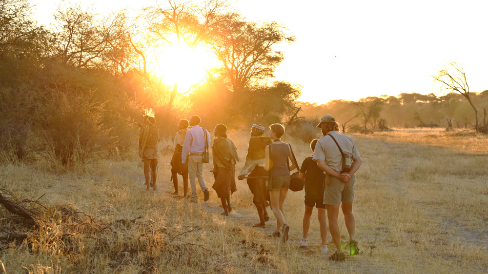 Tourists walking with San people in Botswana, authentic cultural safari experience.