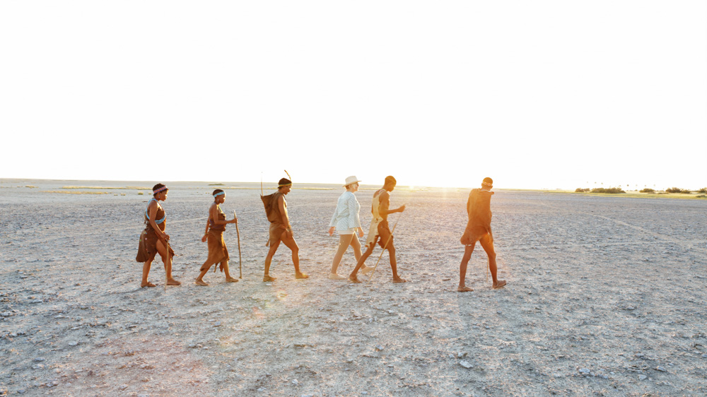 Traveller walking with San Bushmen in the Kalahari Desert, Botswana — authentic safari experience in Africa.
