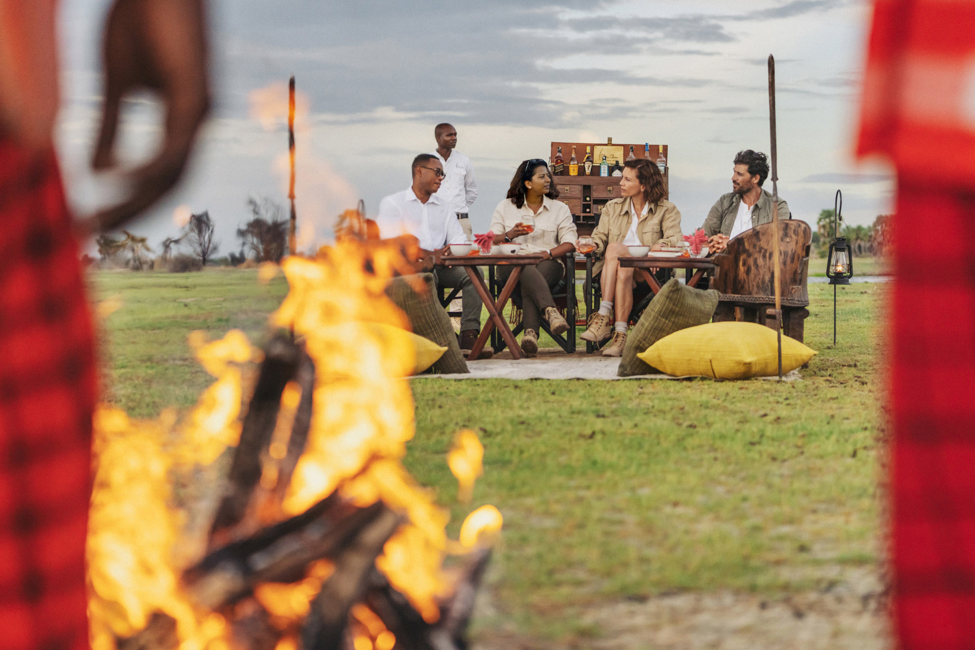Friends gathered around a campfire at Chem Chem Lodge in Tanzania, celebrating life and connection on a luxury safari celebration in Africa.